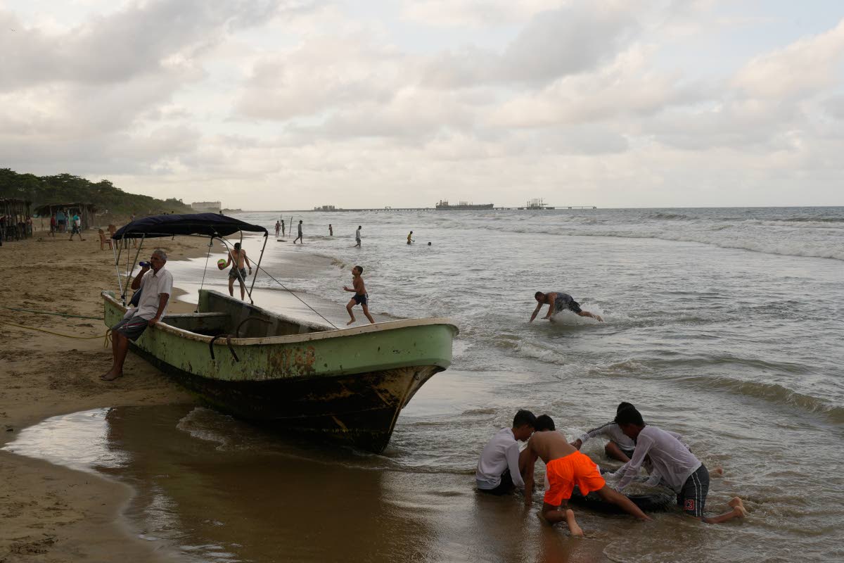 Children play at the beach near El Palito port in Puerto Cabello, Venezuela, Sunday, December 21, 2025. 