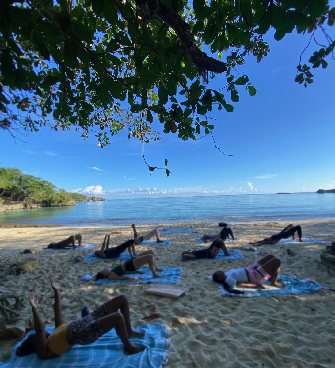 Mat and Flow attendees engage in a glute bridge with extended arms at Winnifred Beach, Portland.