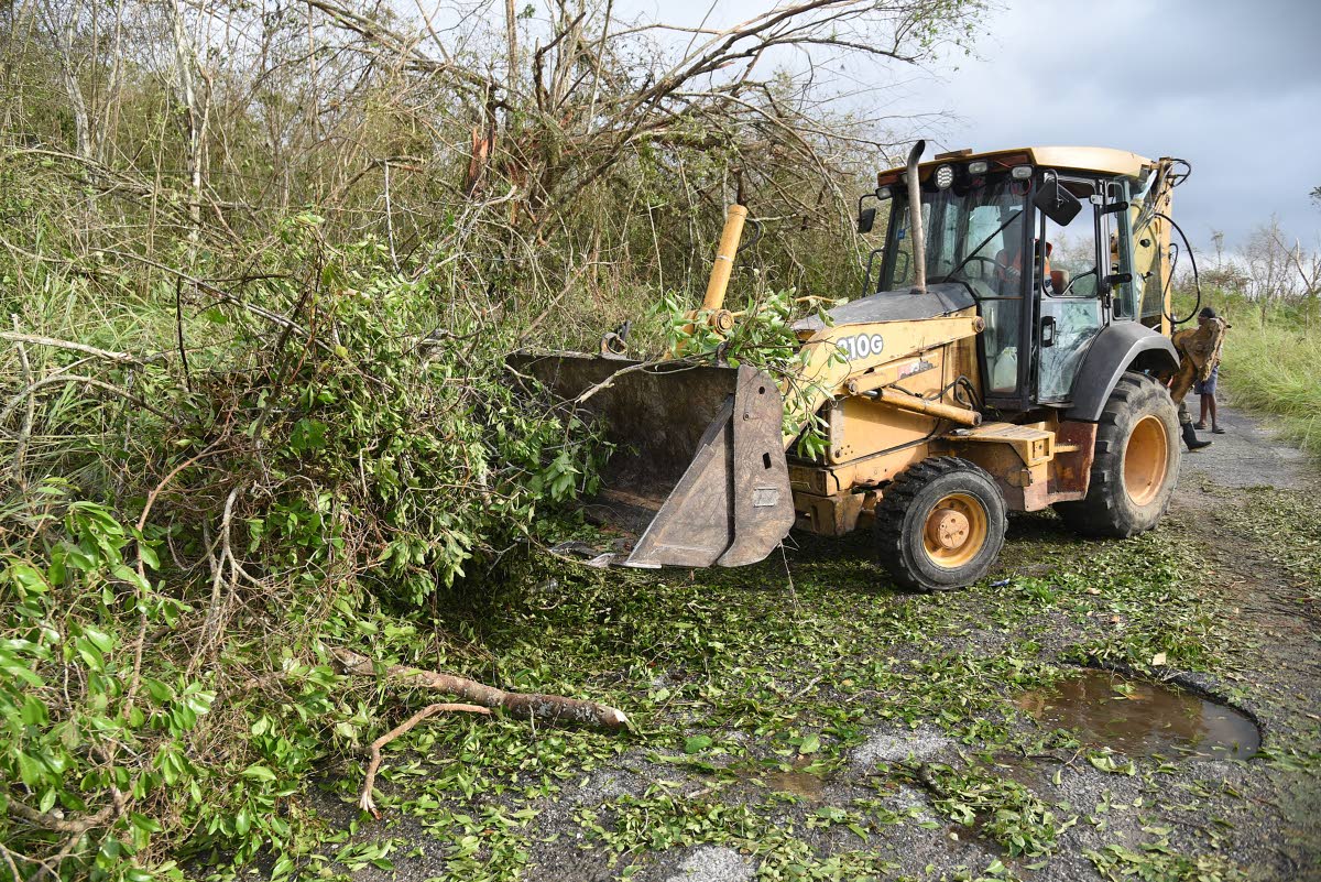 A backhoe clears fallen trees from the Clarks Town–Daniel Town main road in Trelawny after Hurricane Melissa.