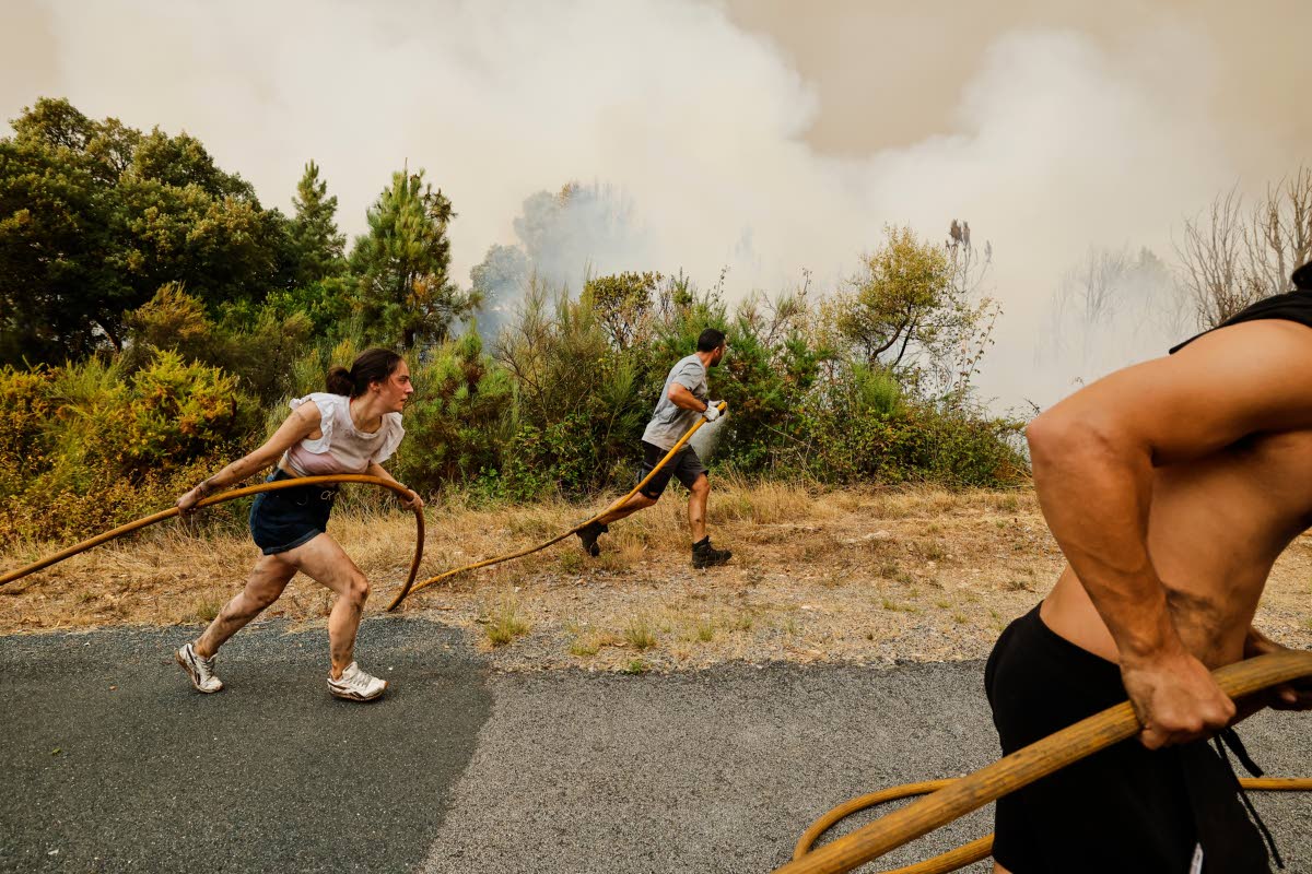 Residents and volunteers work together to battle an encroaching wildfire in Larouco, northwestern Spain, August 13, 2025. 