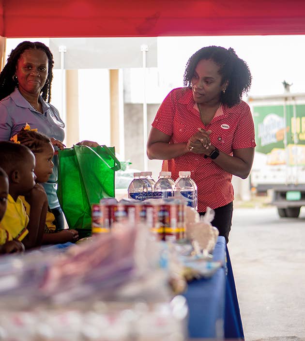Salada Foods General Manager Tamii Brown (right) greets the mini packing line of Jebb Memorial Basic School students at Salada Foods headquarters on Bell Road. Looking on is Jebb Memorial Basic School Principal Leonie Salmon Wong-Sue.