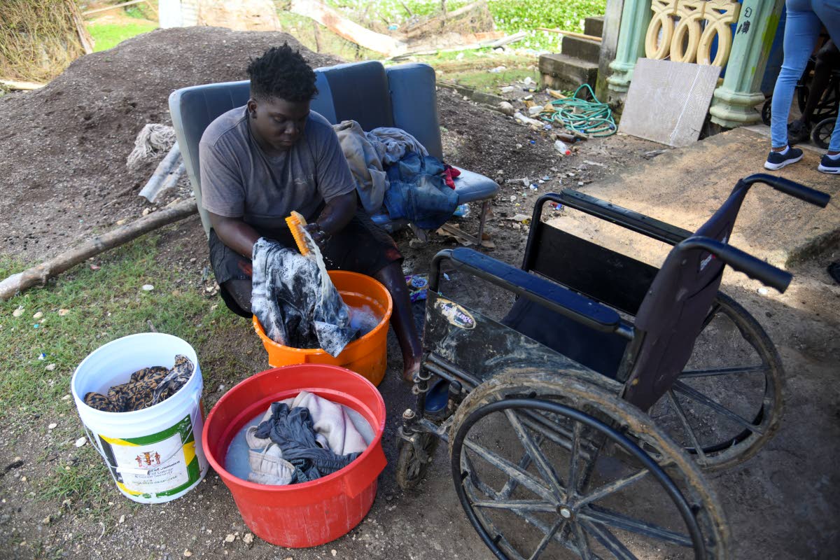 Nineteen-year-old Jowayne Box of New River in St Elizabeth washes clothes in front of his house on January 6. New River was among the communities devastated by Hurricane Melissa.