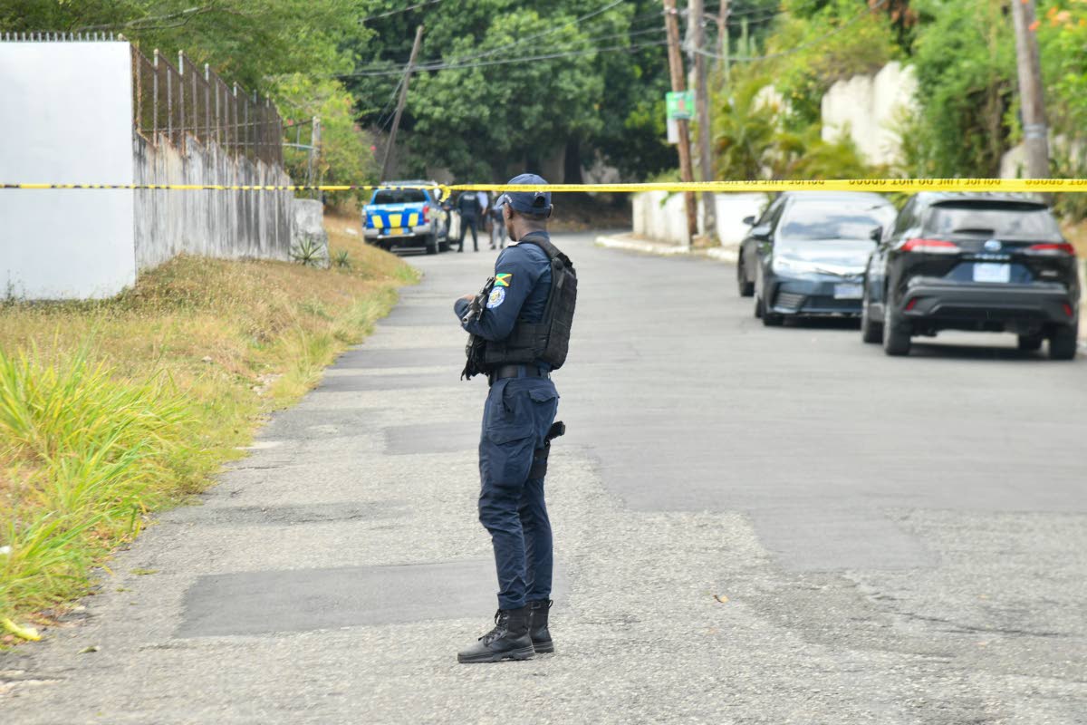 A policeman stands guard at a crime scene on Jacks Hill Road in St Andrew in July last year. 