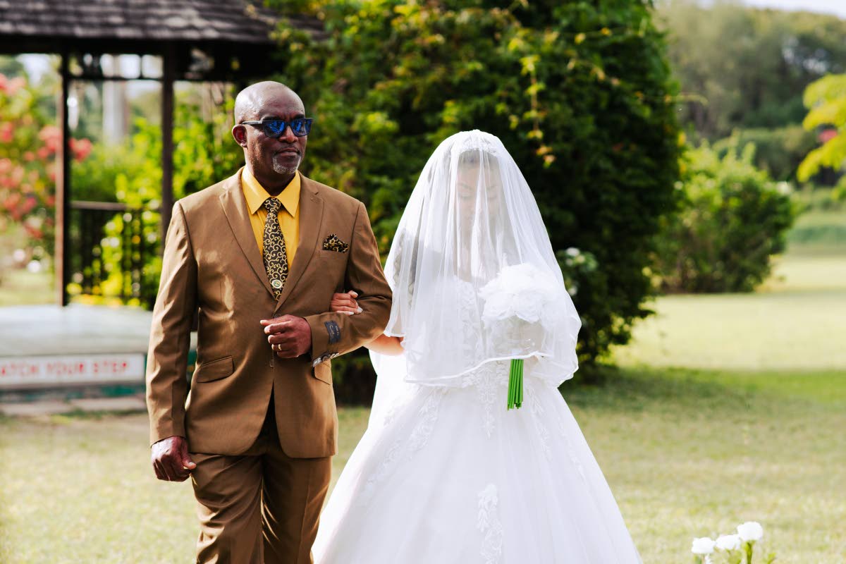 Escorted by her father, Pastor Dwight Reid, the bride, Danielle, makes her way down the aisle.