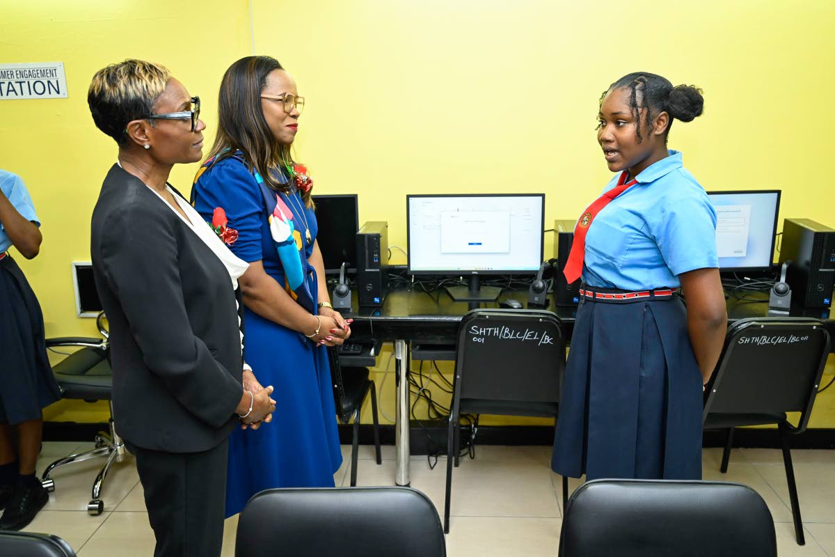 Member of Parliament for St Andrew West Rural Juliet Cuthbert Flynn (left) and Permanent Secretary in the Ministry of Education, Skills, Youth and Information, Dr Kasan Troupe, listen as Stony Hill Technical High School student Sabrina Davis shares details