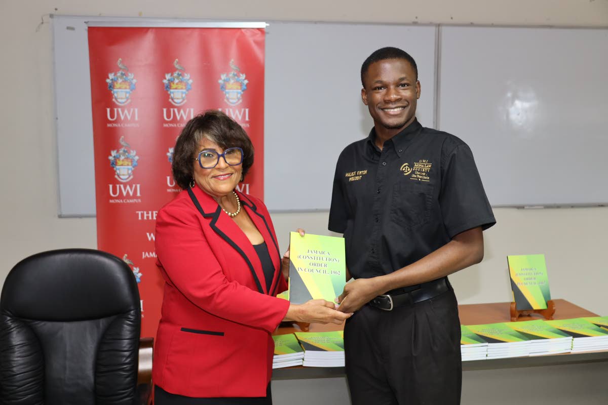 State Minister in the Ministry of Justice and Constitutional Affairs, Marisa Dalrymple‑Philibert, presents a copy of the consolidated Constitution to President of the Mona Law Society, Malieck Kirton (right).