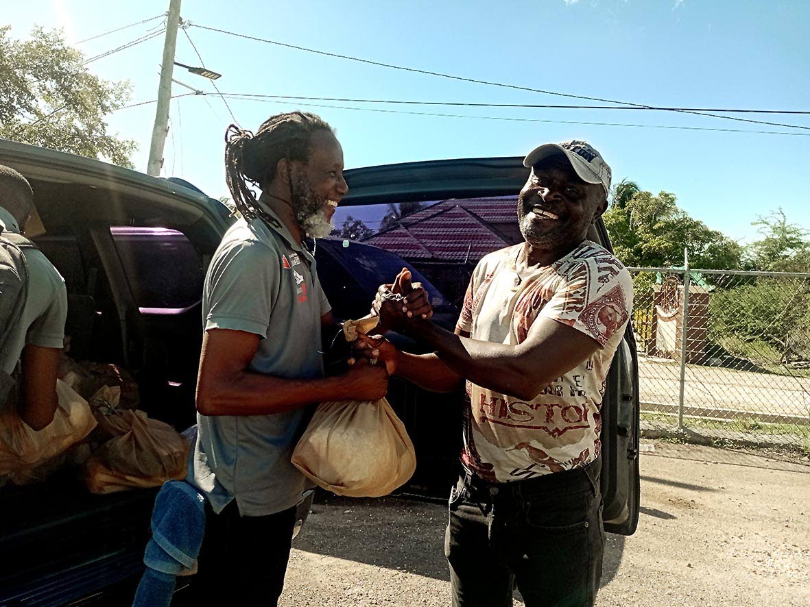 Garth Staple (left), facilitator at the Violence Prevention Alliance (VPA), presents a care package to a fisherman at Rocky Point in Clarendon. Occasion was a community outreach initiative executed by the VPA at Rocky Point recently. Community members were