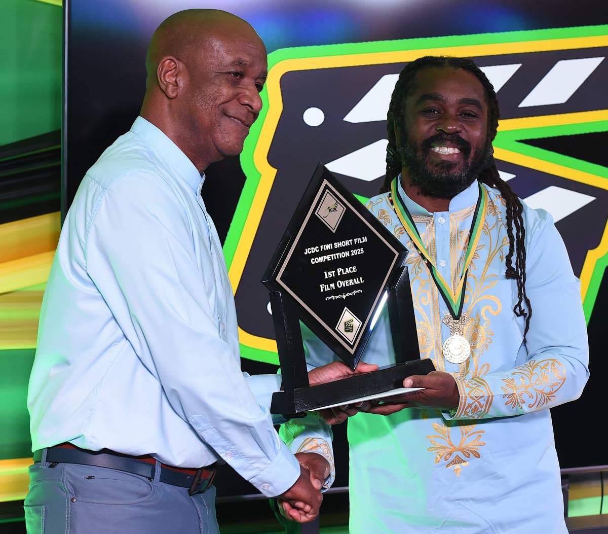 Lenford Salmon (left), executive director, Jamaica Cultural Development Commission, presents Omaall Wright with the  first place trophy after he won the Fiwi Short Film Competition.