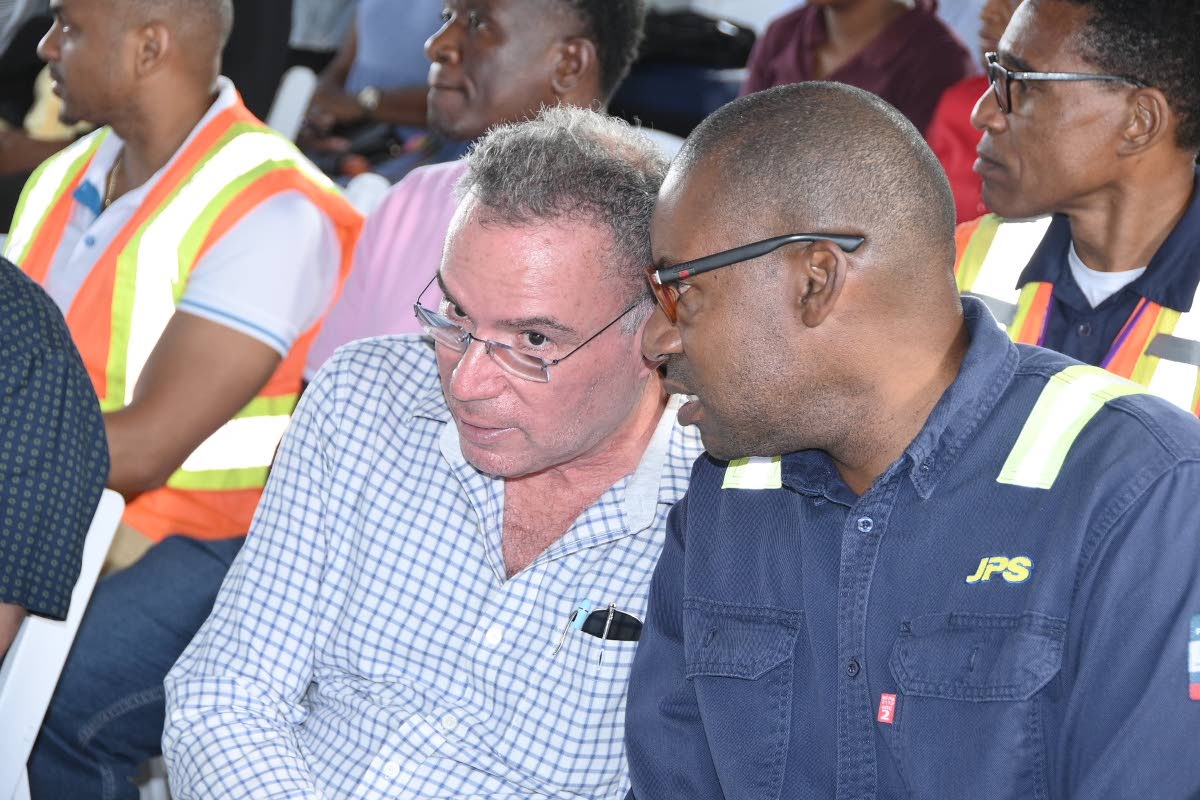 Energy Minister Daryl Vaz (left) gives JPS President Hugh Grant a listening ear during the recent commissioning of an emergency mobile power-generating unit in Darliston, Westmoreland.
