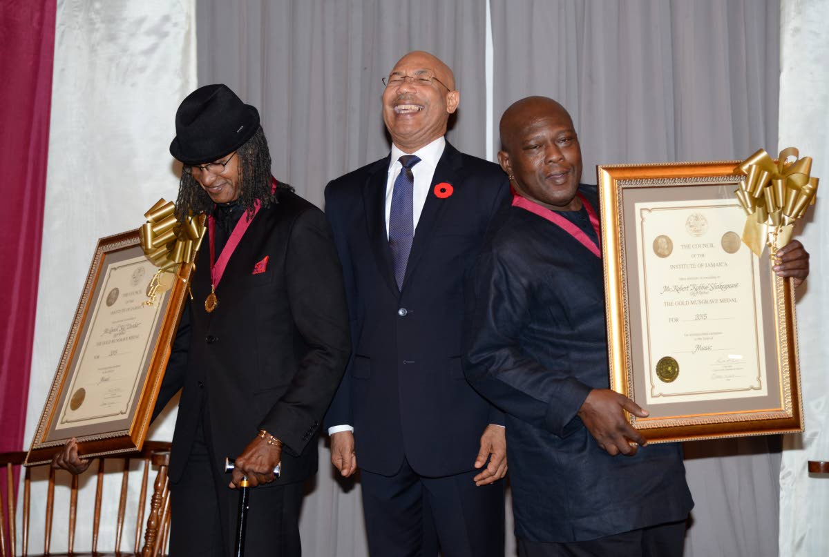 

Governor General Sir Patrick Allen (centre) laughs as he is flanked by drummer Sly Dunbar (left) and bass guitarist Robbie Shakespeare after they received Gold Musgrave Medals in the field of music at the Institute of Jamaica in 2015.