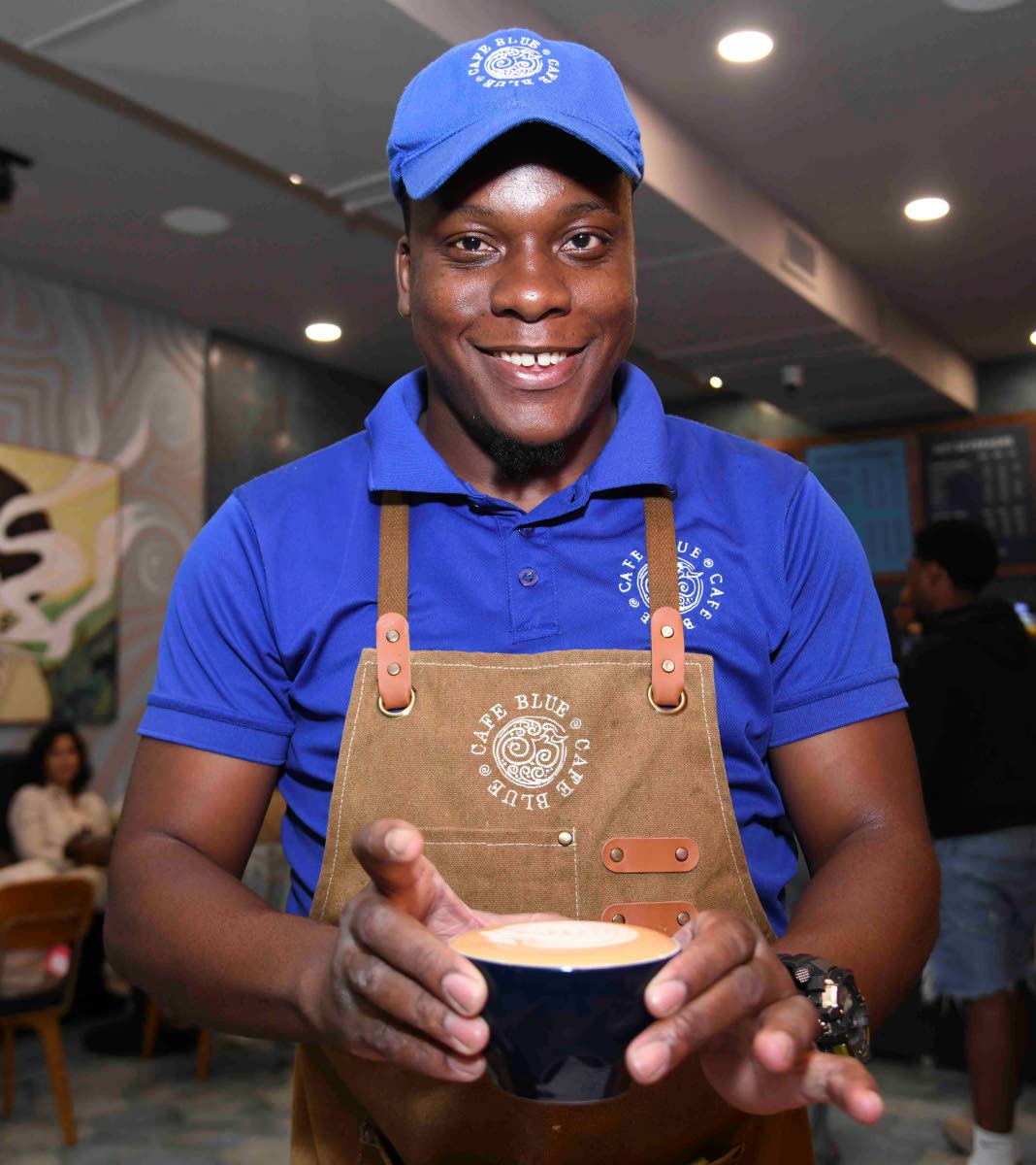 Award-winning barista, Romelle Bailey, presents a fresh cup of coffee with a smile.