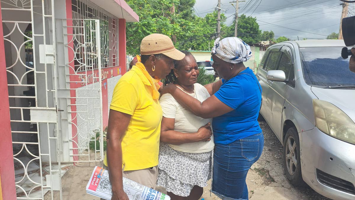 Marcia Stewart (centre), mother of Demoy Campbell, being comforted by neighbours.