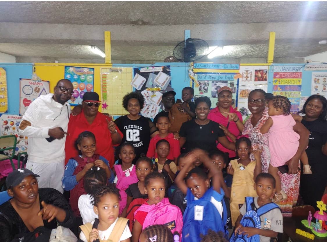 CEO of JAMCO Entertainment Michael Small (back row left) poses for a photograph with staff and students at the Mount Olivet Basic School in St James.
