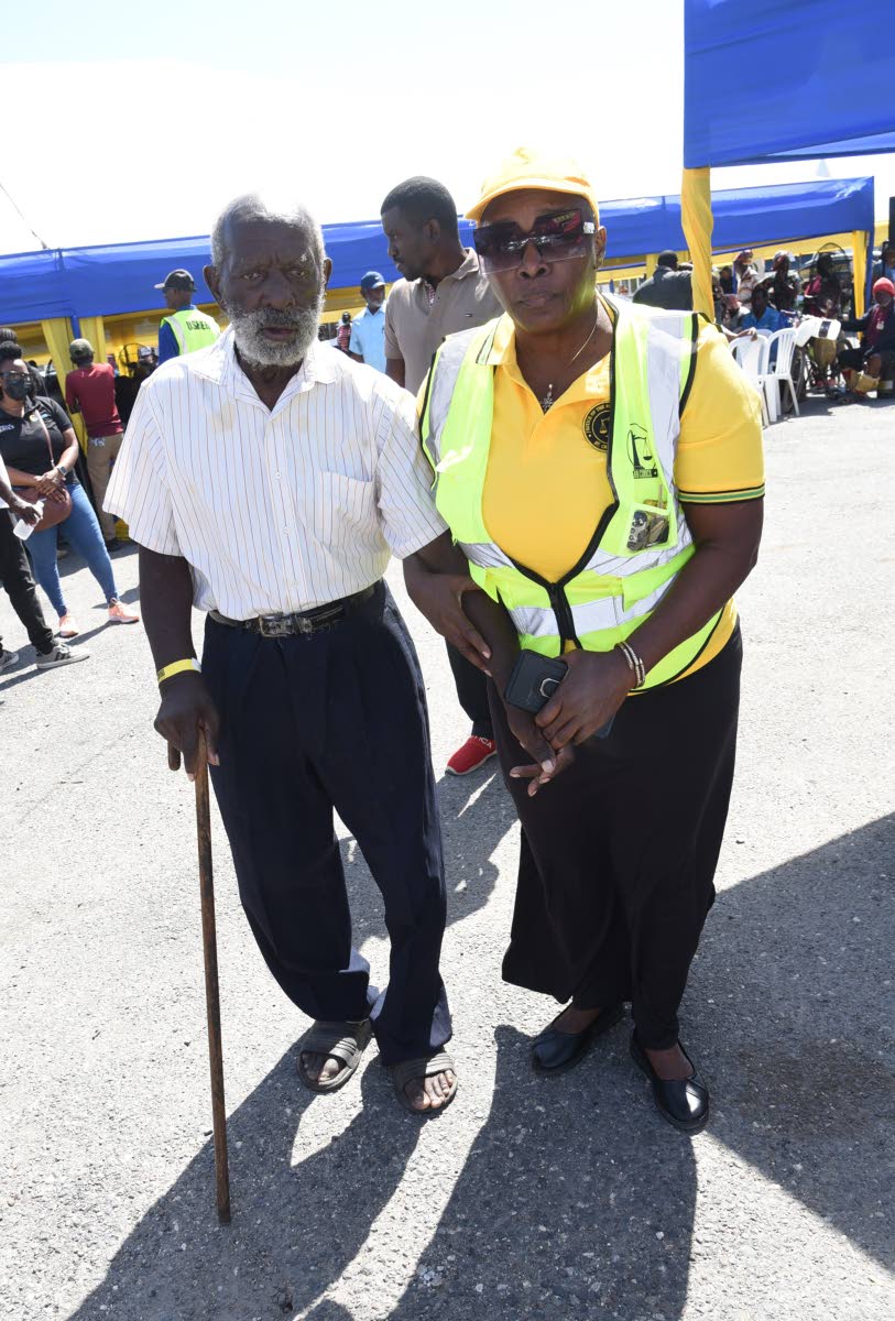 Miriam Levy (right), a justice of the peace, assists Joseph Bennett (left), who is visually impaired, to the bathroom during the Ministry of Justice Legal Aid Council Justice Fair for Persons with Disabilities.