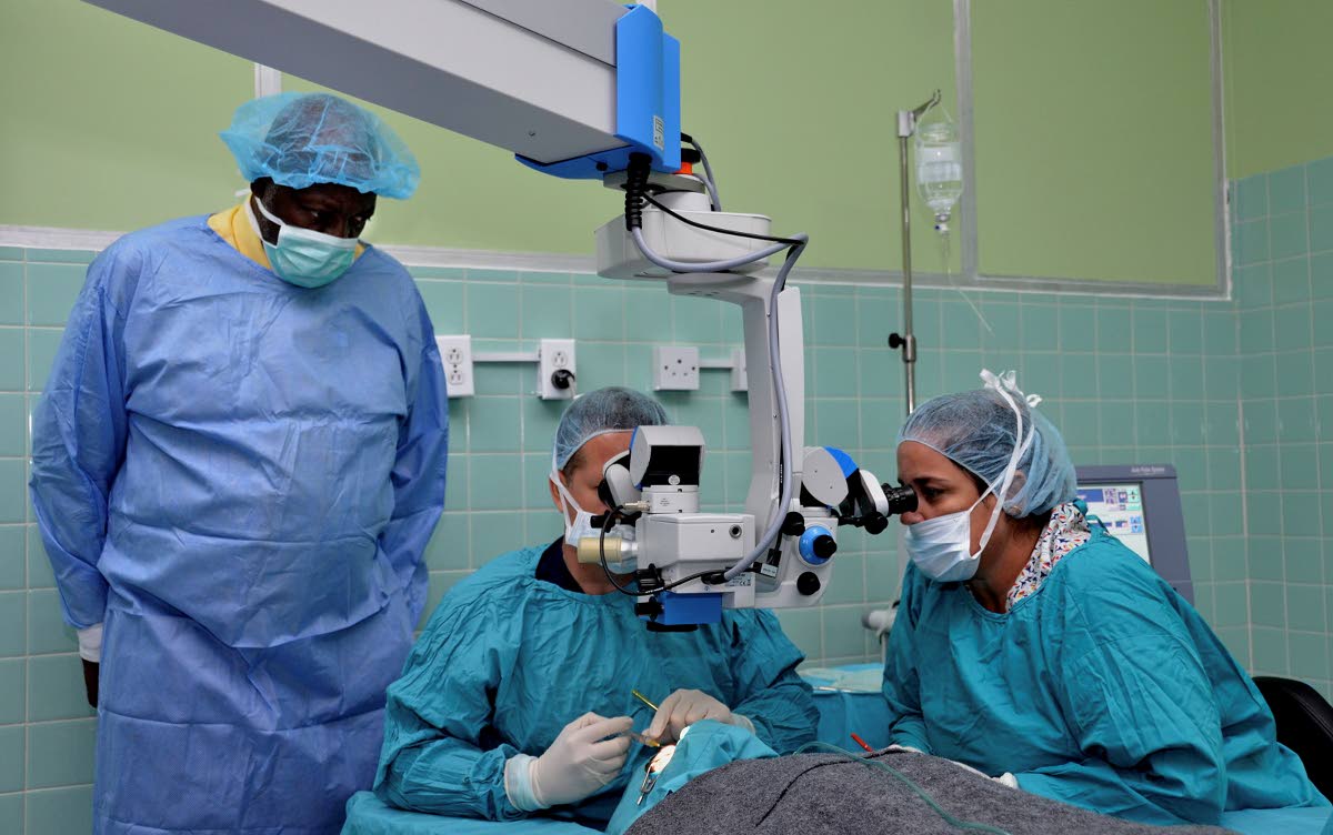 Cuban specialists (seated) perform eye surgery on a patient at the Opthalmology Centre, under the Jamaica/Cuba Eye Care Programme in 2013. Looking on is Health Minister Dr Fenton Ferguson.