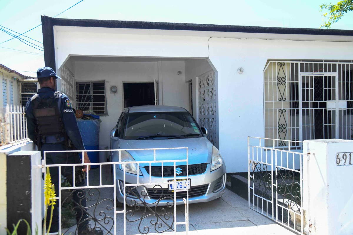 The police inspect a house on Marlin Way in Braeton, Portmore, in St Catherine yesterday where a woman and her daughter were reportedly attacked by a man believed to be of unsound mind. 