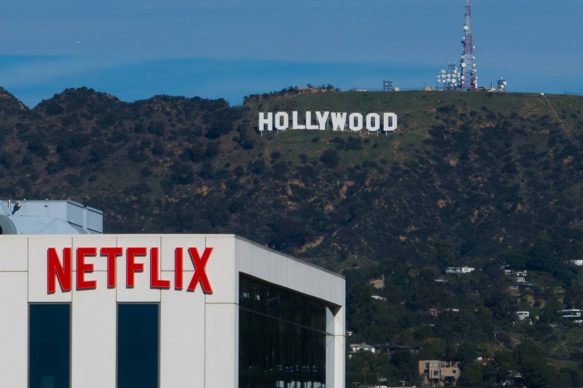 A Netflix sign is displayed atop a building in Los Angeles, on December 18, 2025, with the Hollywood sign in the distance. 