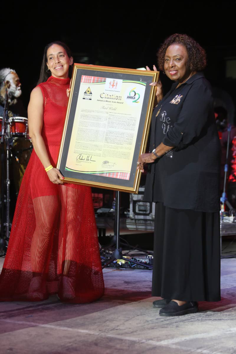 Minister of Culture, Gender, Entertainment and Sport, Olivia Grange, presents a framed citation to Stephen ‘Cat’ Coore’s daughter, Kanna Coore. 