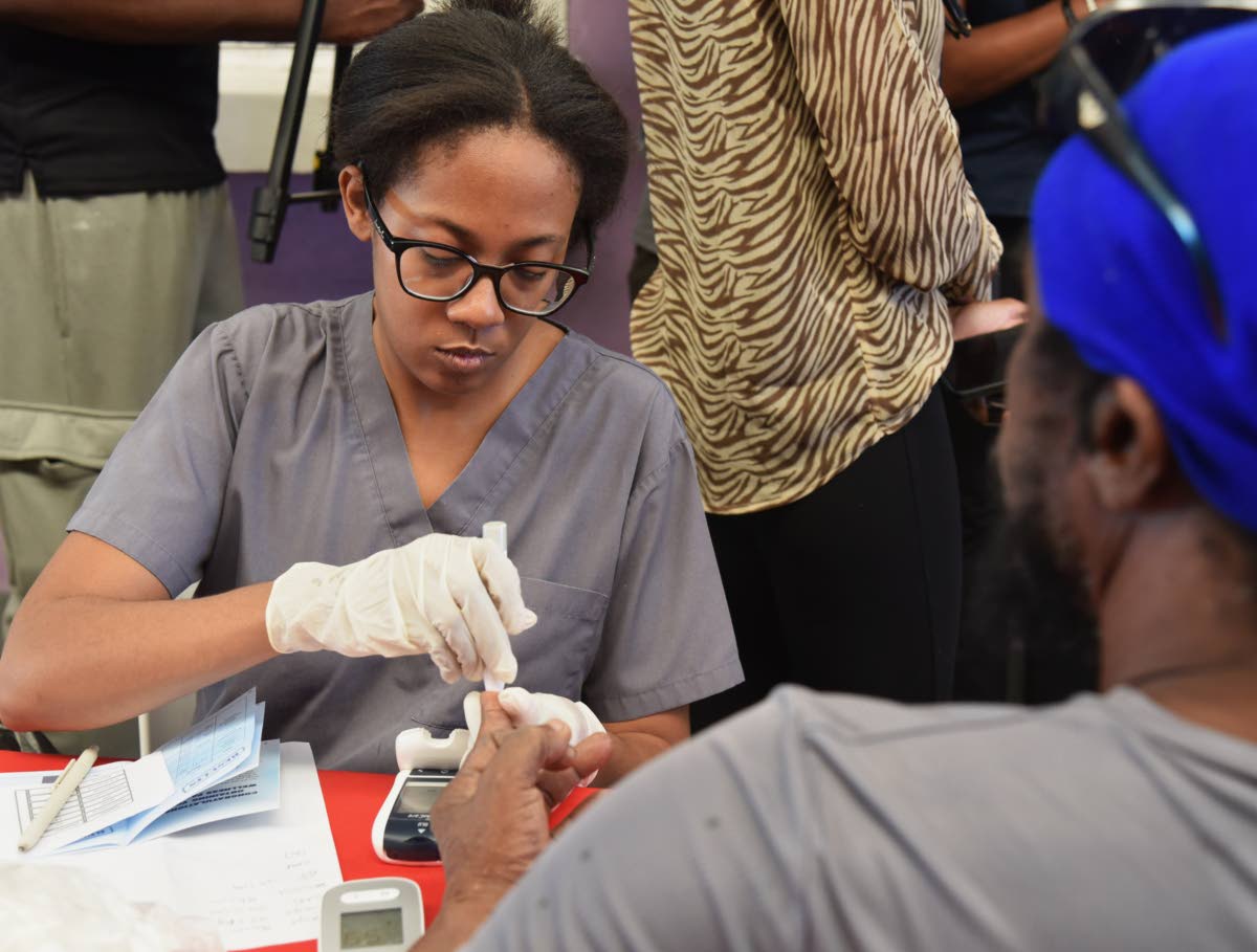 Dr Shauna Martin Lee (left) conducts a diabetes test on a patient at the Kingston and St Andrew Municipal Corporation Health Expo, held on Wednesday at the Jubilee Commercial Centre, West Parade, downtown Kingston.