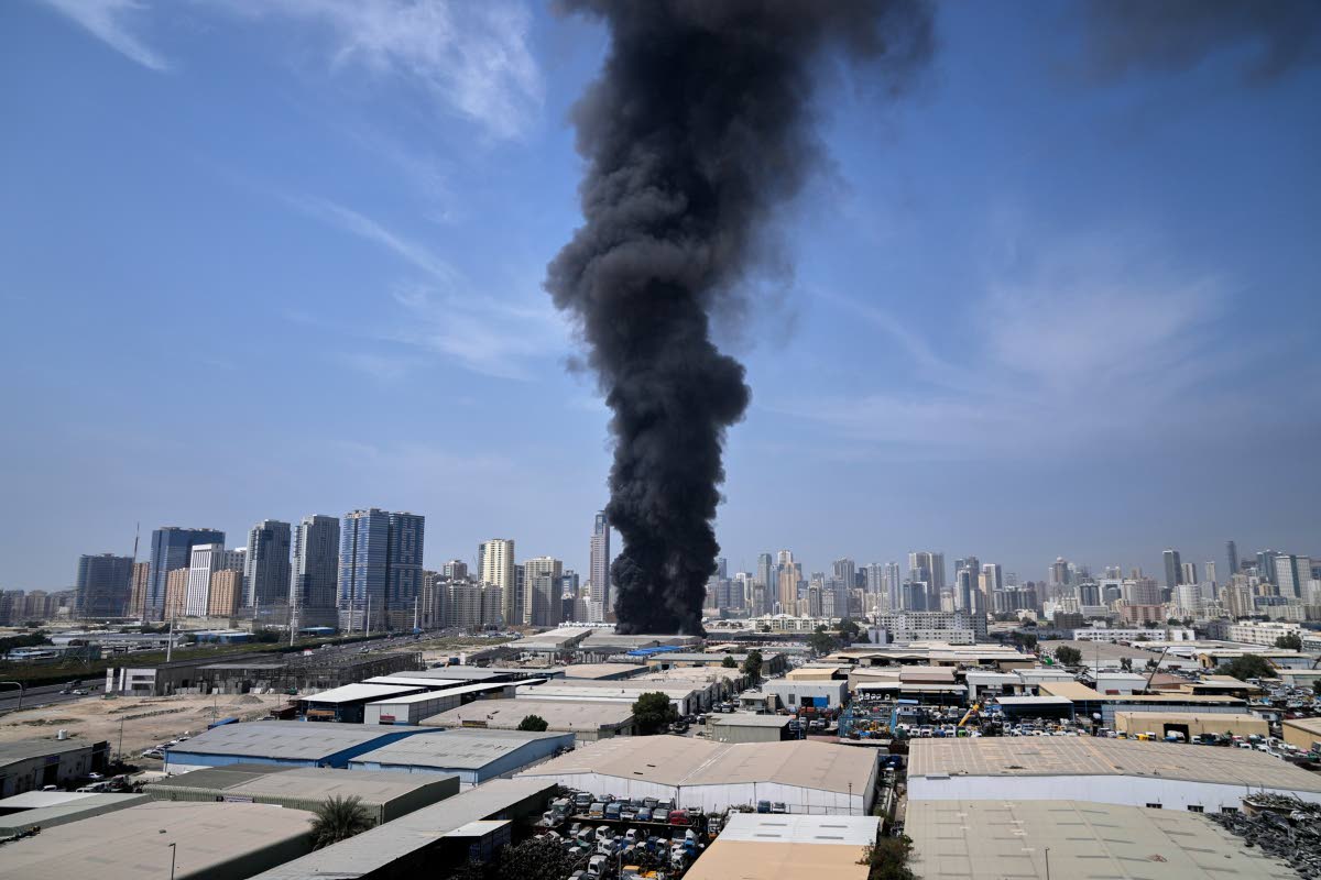 A black plume of smoke rises from a warehouse at the industrial area of Sharjah City in the United Arab Emirates following reports of Iranian strikes in Dubai, United Arab Emirates on March 1, 2026. (AP Photo/Altaf Qadri)