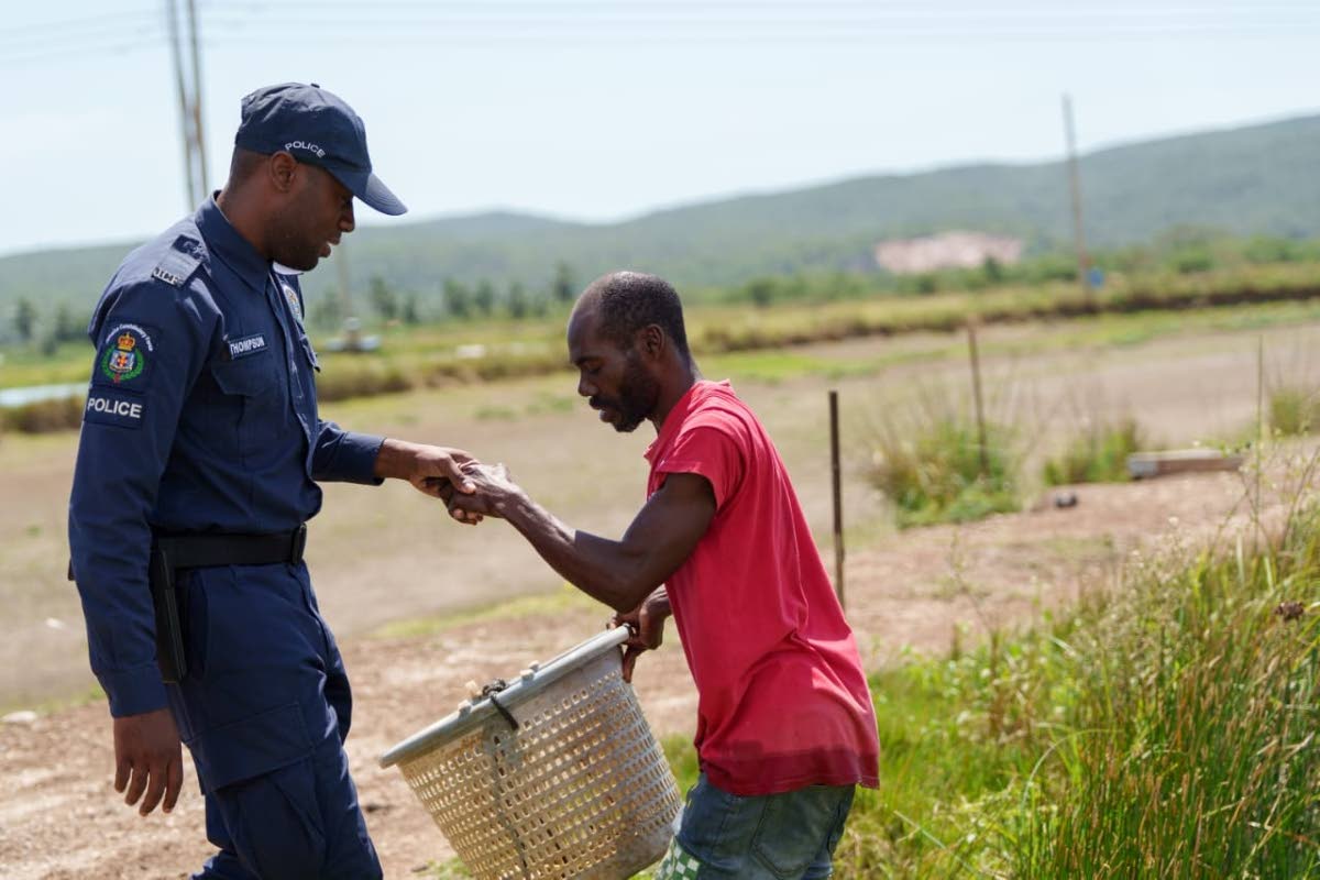 Constable Dayton Thompson of Jamaica Constabulary Force’s Agricultural Protection Branch (APB) interacts with a farmer in Hill Run, St Catherine.