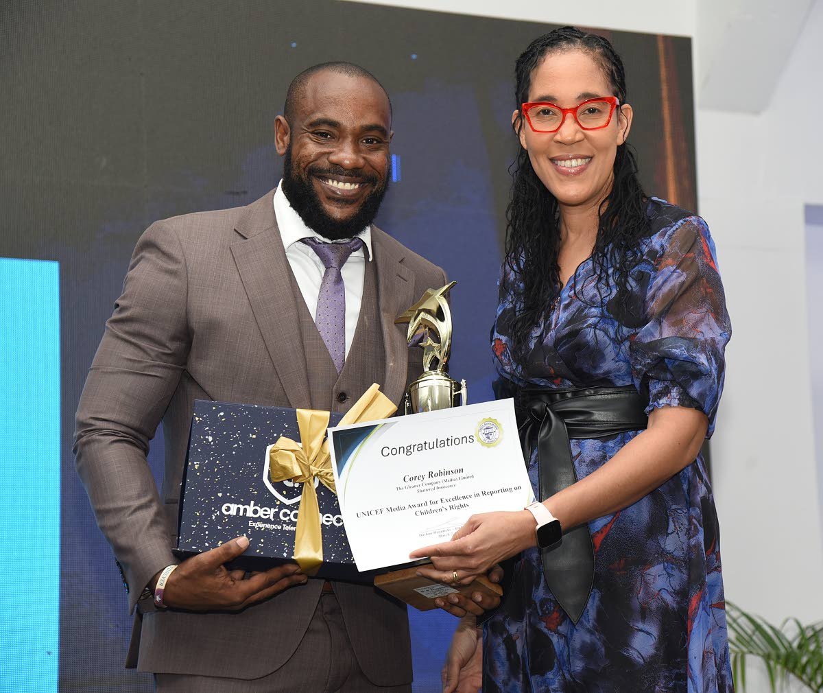 The Gleaner’s Corey Robinson (left) collects the UNICEF Media Award for Excellence in Reporting on Children’s Rights from Donna-Marie Rowe, communication specialist at UNICEF Jamaica.