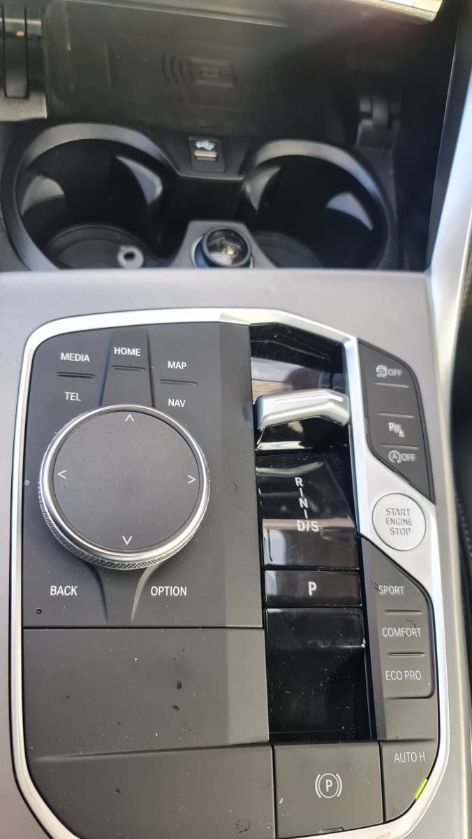 A close-up of the tactile control hub, where the minimalist gear toggle sits alongside the signature iDrive rotary controller, allowing for intuitive navigation of the vehicle’s many sub-systems.