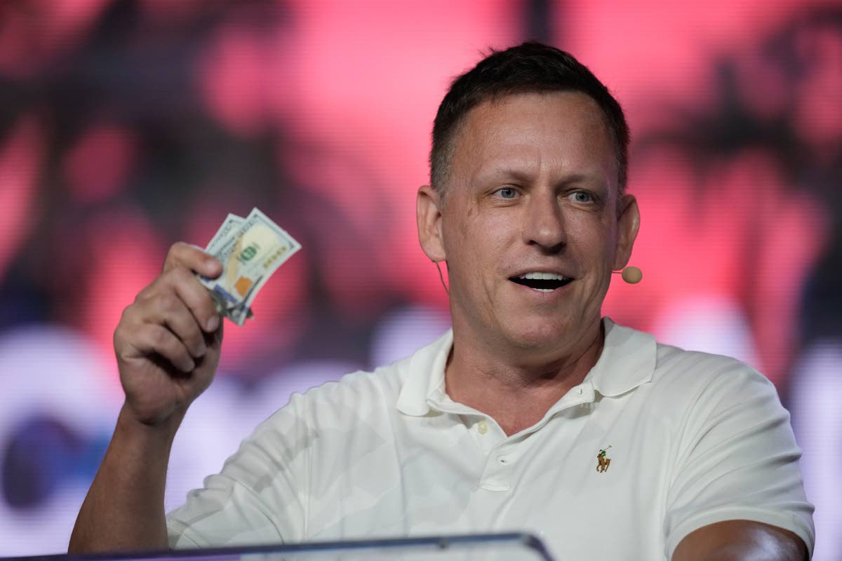 AP 
Peter Thiel, co-founder of PayPal and Palantir, offers a pair of hundred dollar bills to attendees during a keynote address at the Bitcoin Conference, April 7, 2022, in Miami Beach, Florida, USA. 