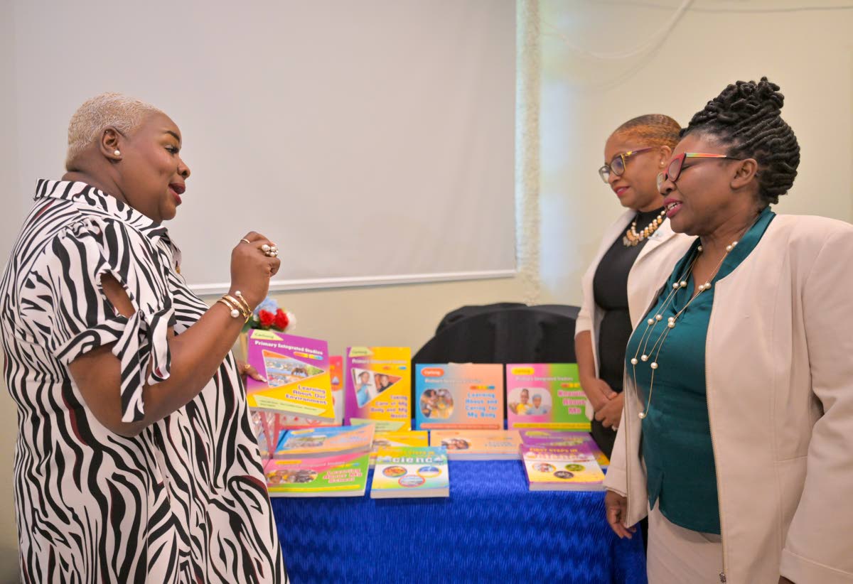 Assistant Chief Education Officer in the Ministry of Education, Skills, Youth and Information’s Media Services Unit, Dr Nadine Simms (right), and National Education Trust (NET) Executive Director, Latoya Harris-Ghartey (centre), are briefed on textbooks 