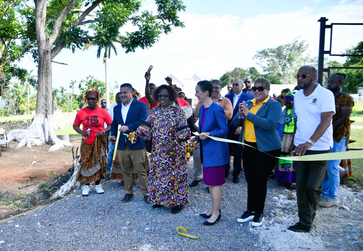 Minister of Culture, Gender, Entertainment and Sport, Olivia Grange (third left), cuts the ribbon on Friday to officially open two African-style houses constructed by the Ghana Army Engineer Reconstruction Team at Seville Heritage Park in St Ann. She is jo