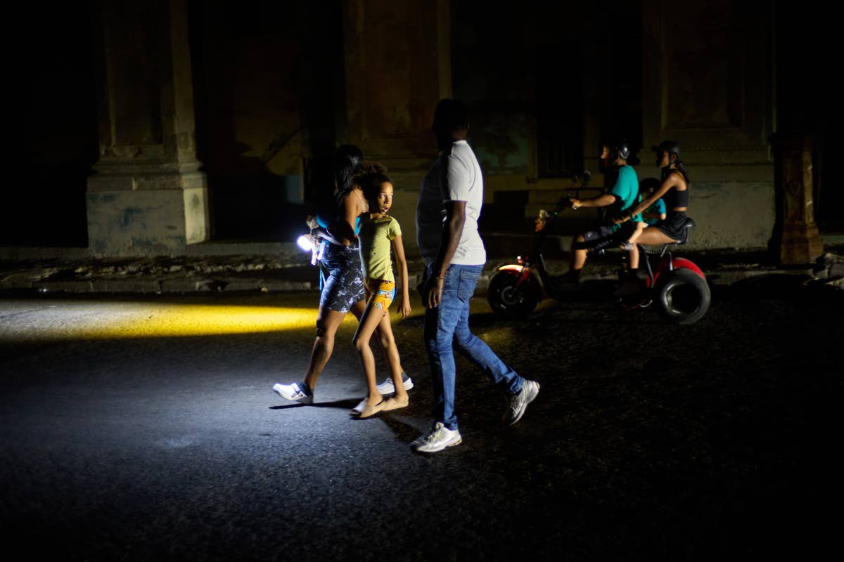 People walk on a street during a blackout in Havana, Monday, March 16, 2026. 