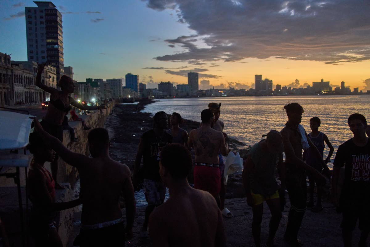 People watch the sunset from the Malecón during a blackout in Havana, Monday, March 16, 2026. 