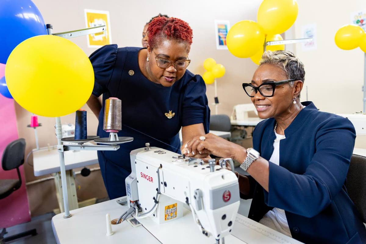 State Minister in the ministry of National Security and Peace, Juliet Cuthbert-Flynn (right), is being assisted by Chief Technical Director in the ministry, Shauna Trowers, with threading a sewing machine in the new sewing lab at the South Camp Juvenile Co