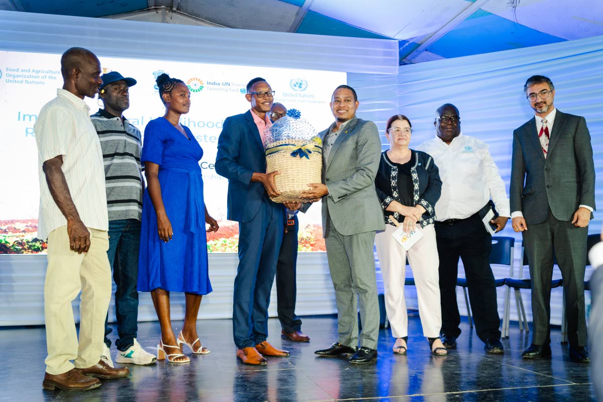 Keneil Gray (fourth left), supported by fellow project beneficiaries, presents Floyd Green (fourth right), minister of agriculture, fisheries and mining, with a produce basket in the presence of Dr Ana Touza (third right), FAO representative for Jamaica, T