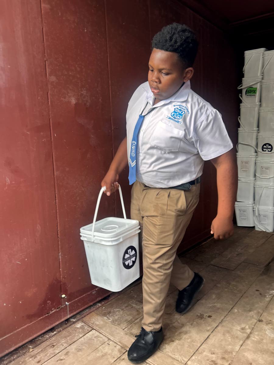 A student from Broughton Primary School helps to unload emergency food kits for Broughton during the distribution exercise in Westmoreland.