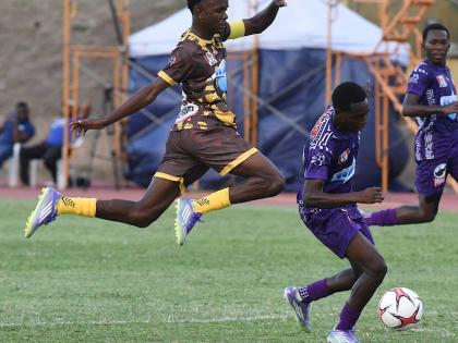 Andre Langford (left) of Charlie Smith High moves to tackle Kajay Fletcher of Kingston College during their Manning Cup football match at the Stadium East field last Saturday.