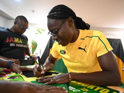 
Roneisha McGregor signs a Jamaican flag during a visit to the Jamaican Embassy in Tokyo.