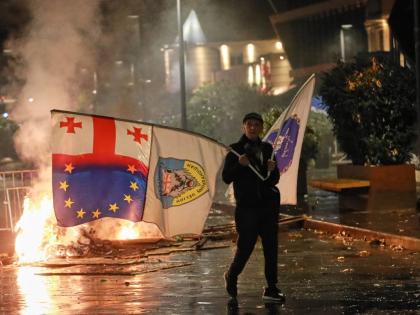 A demonstrator with a Georgian national, EU and other flags walks in front of police line during an opposition rally in the city centre of Tbilisi, Georgia.