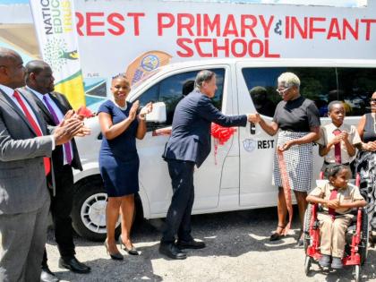  Parliamentary Secretary, Ministry of Education, Skills, Youth and Information, Senator Marlon Morgan (second left), applauds as Ambassador of Japan to Jamaica, His Excellency Yasuhiro Atsumi (fourth left), hands over the keys for a bus valued at over US$4