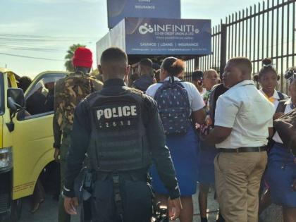 An officer from the St. Catherine North Division of the Jamaica Constabulary Force (JCF) monitors students as they board transportation, ensuring they get to school on time as he carries out activities under the ‘Operation Learn, Not Loiter’ initiative