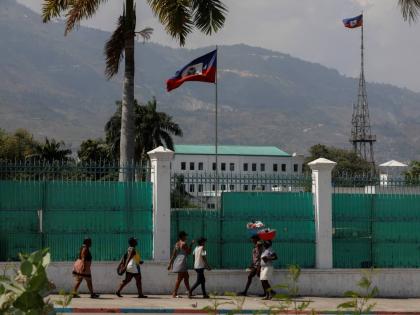 People walk past the National Palace in Port-au-Prince, Haiti, Monday, March 25, 2024. (AP Photo/Odelyn Joseph)