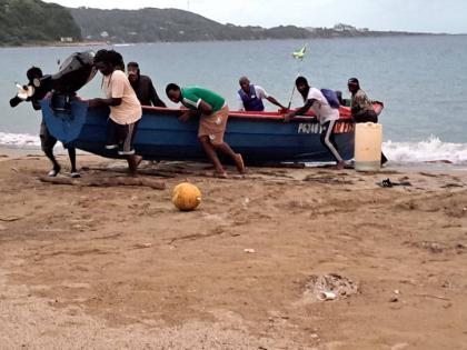 Left: Fishermen in Port Maria bringing their vessel to shore.