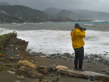 A man takes photographs of the rising waves at Caribbean Terrace in Kingston, as Hurricane Melissa approaches Jamaica.