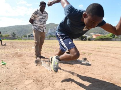 Track and field coach Carl Page (left) helps one of his charges, Jhadon Burke, manage his starts during a training session at the Bridgeport High School in 2023.