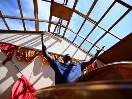  Gladstone Taylor/Multimedia Photo Editor 
Sherman Graham, pastor of Brucefield Gospel Chapel in Brucefield, St Elizabeth, in a moment of reverence at the pulpit of his roofless church on Thursday. The church is one of several across western Jamaica batter