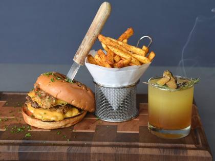 The featured storm breaker burger, served with fries, stood proudly in the good company of this smoky Amber elixir cocktail.
