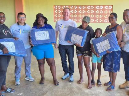 Century Aluminum’s executives, Eliezer Batista (second left) and Kenneth Calloway (centre), along with Jamalco equipment operator, Keon Sutherland (right), distribute tarpaulins to residents of Vineyards, St Elizabeth. They were part of a 30-member Jamal