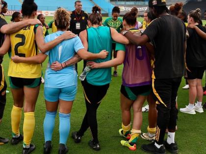 Reggae Girlz coach Hubert Busby takes his charges through a team talk.