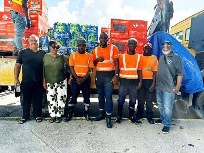 Beverly Nichols (second right) poses with volunteers and the shipment of solar generators and bottled water donated by her Push Start Foundation.
