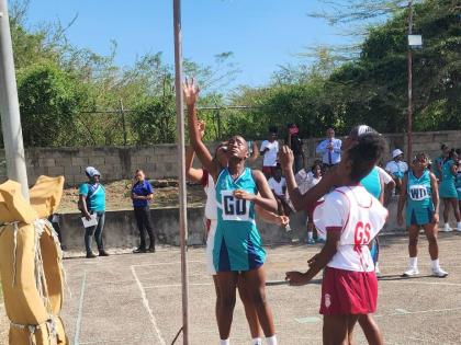 Denbigh High goal defence Cheyenne Mills (left) looks on as Kemps Hill High goal shooter Ashanne Gallimore (right) sinks one of six goals for her team in Thursday’s ISSA rural schoolgirls under-19 match at Denbigh. Denbigh defeated their opponents 68-6.